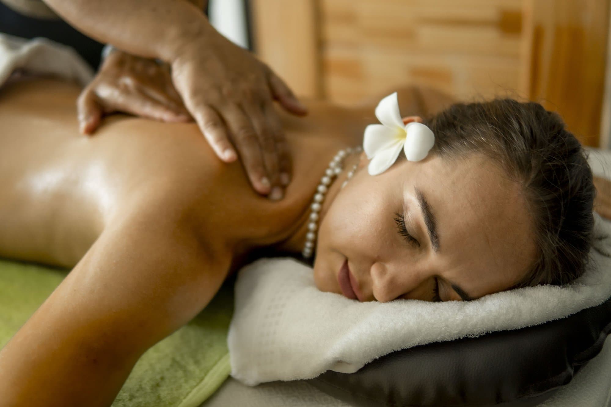 A therapist's hands working along a guest's back during an oil massage