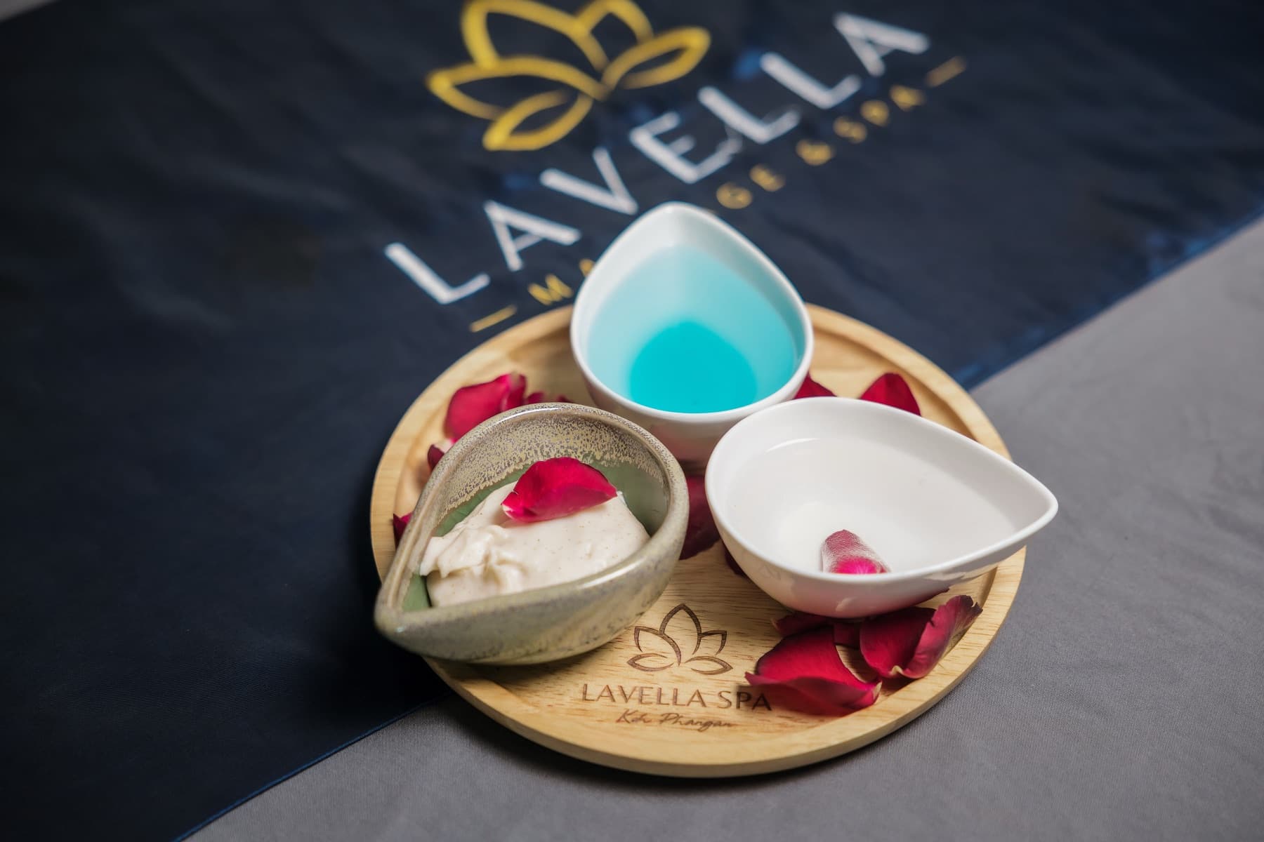 Lavella's own scrubs and oils on a wooden tray, with rose petals