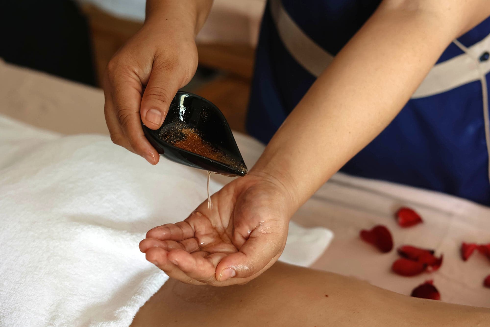 A therapist pouring warm oil into her hand at Lavella Spa